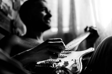 Evde gitar çalan adam.
