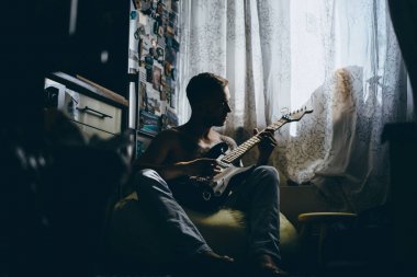 Evde gitar çalan adam.