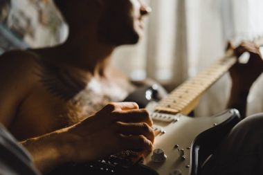 Evde gitar çalan adam.