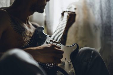 Evde gitar çalan adam.