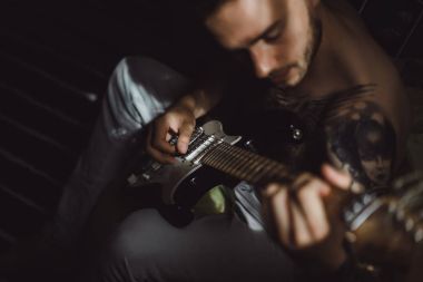 Evde gitar çalan adam.