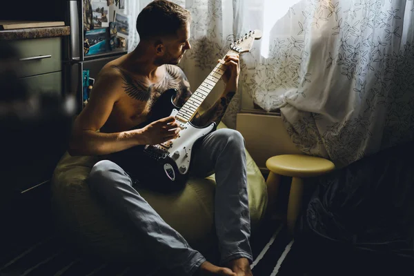 A férfi otthon gitározik. — Stock Fotó
