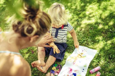 sarışın yakışıklı genç anne ile açık yeşil çimenlerin üzerinde çizim