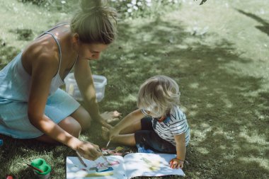 sarışın yakışıklı genç anne ile açık yeşil çimenlerin üzerinde çizim