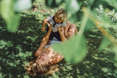 sevimli sarışın çocuk oynamak genç anne ile açık yeşil çimenlerin üzerinde