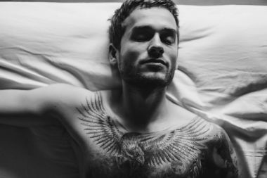 Yatakta dövmeli adam 