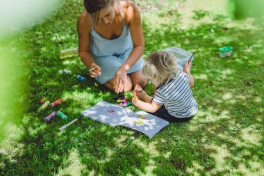 sarışın yakışıklı genç anne ile açık yeşil çimenlerin üzerinde çizim