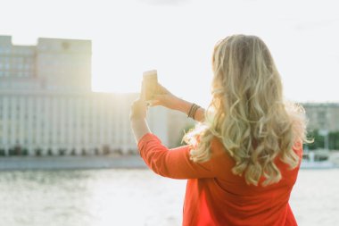 sarışın genç kadın arkası ile telefon açık kırmızı ceketli