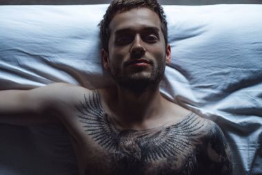 dövmeli adam yatakta yatan 