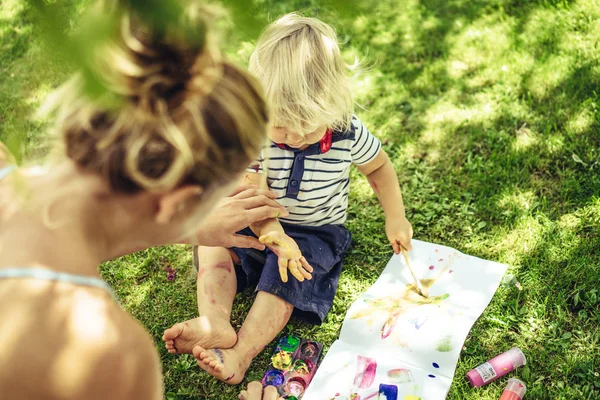 sarışın yakışıklı genç anne ile açık yeşil çimenlerin üzerinde çizim