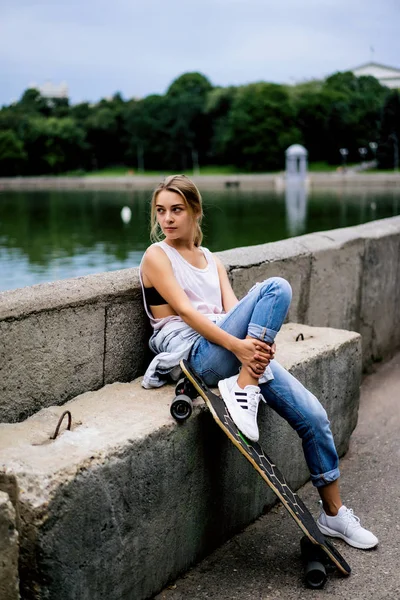 Menina no cais sentado com longboard — Fotografia de Stock