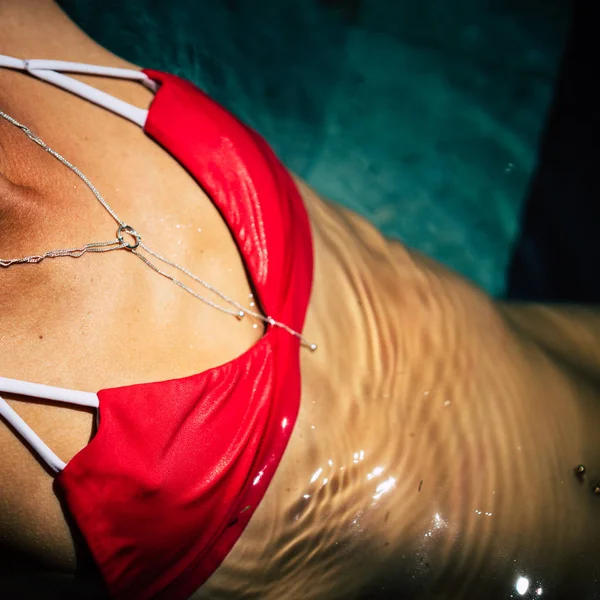 赤い水着でシルバー アクセサリーと美しい女性のクローズ アップの日光浴を取る — ストック写真