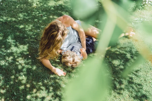 Söt Blond Pojke Med Ung Mamma Liggande Grönt Gräs Utomhus — Stockfoto