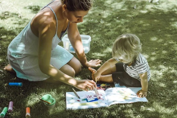 Mignon Garçon Blonde Dessin Avec Jeune Mère Sur Herbe Verte — Photo