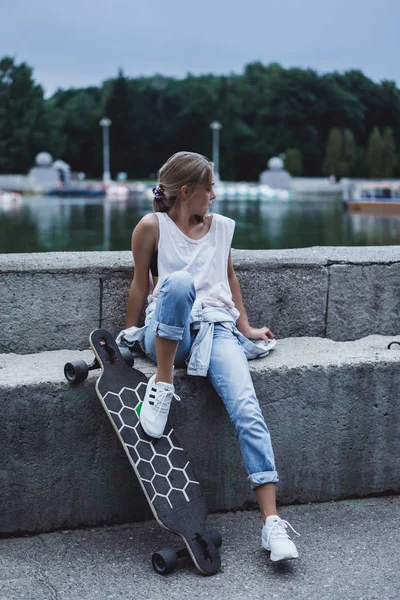 Chica en muelle sentado con longboard — Foto de Stock