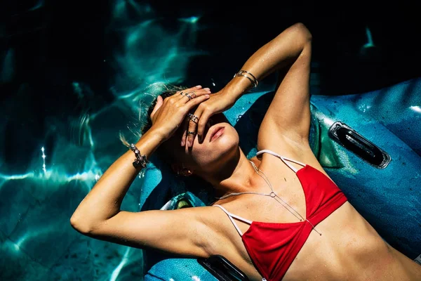 close-up of beautiful woman with silver accessories in red swimming suit take sunbath