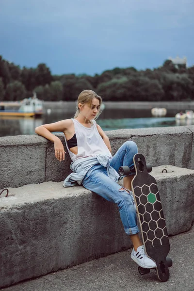 Meisje op de kade met longboard — Stockfoto