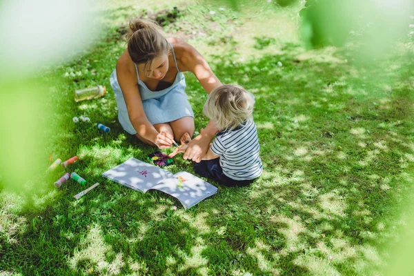 sevimli sarışın çocuk genç anne açık yeşil çimenlerin üzerinde çizim ile