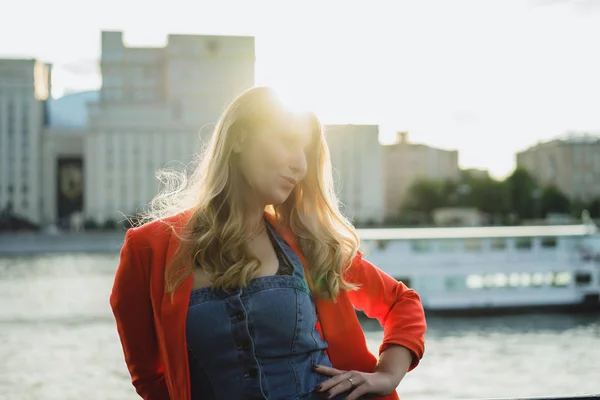 日没時に屋外の赤いジャケットの若いブロンドの女性 — ストック写真