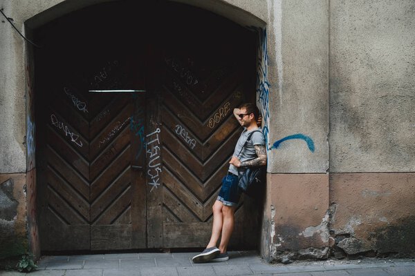 Человек, опирающийся на деревянную стену
