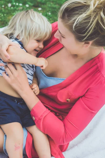 sarışın genç kadın oynamak sevimli çocukla açık yeşil çimenlerin üzerinde