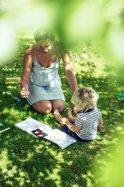 sevimli sarışın çocuk üzerinde yeşil çim açık genç anne ile