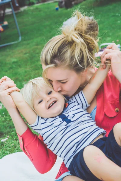 Ung Mamma Kysser Söt Blond Pojke Grönt Gräs Utomhus Sommaren — Stockfoto