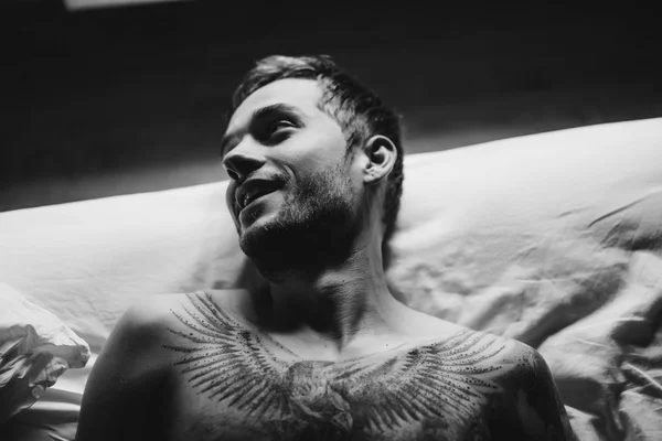 Tattooed man smiling in bed