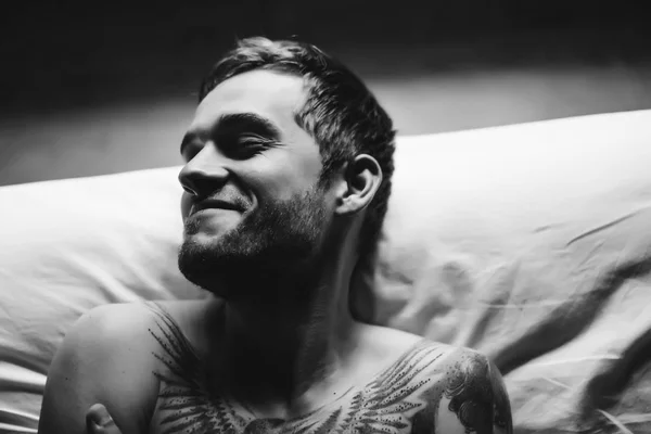 Tattooed man smiling in bed