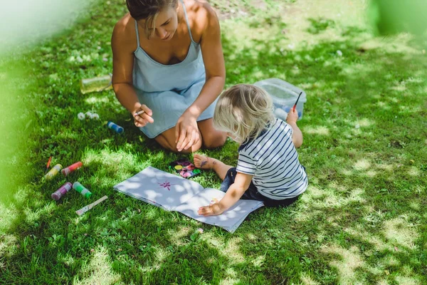 sevimli sarışın çocuk genç anne açık yeşil çimenlerin üzerinde çizim ile
