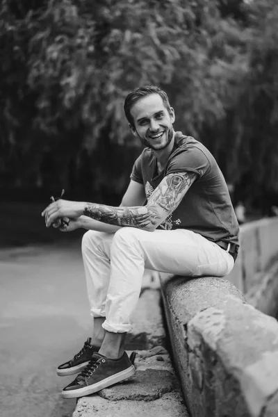 Mann sitzt auf Zaun und lächelt in Kamera — Stockfoto
