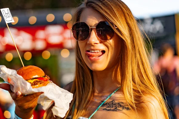 young woman eating a burger at a street food festival