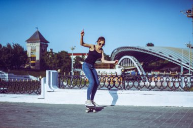 Güzel genç patenci kadın şehirde onu longboard sürme. Sokak kıyafetleri içinde şık kız uzun bir tahta üzerinde sürmek.