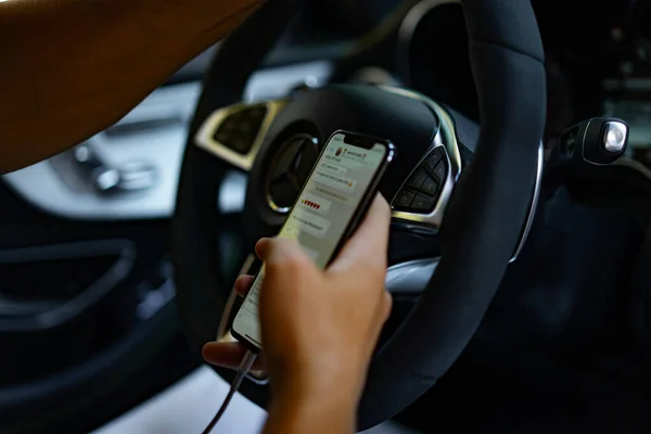 Een man die een auto bestuurt schrijft een bericht op een smartphone — Stockfoto