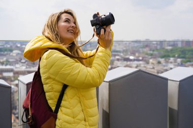 Seyahatte olan bir kadın şehrin fotoğraflarını yüksek bir yerden çekiyor. Kameralı bir kadın. Kadın fotoğrafçı
