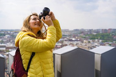 Seyahatte olan bir kadın şehrin fotoğraflarını yüksek bir yerden çekiyor. Kameralı bir kadın. Kadın fotoğrafçı