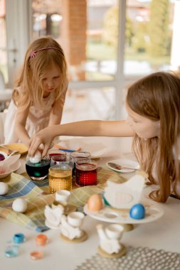 Anne ve kızları yumurta boyuyor. Mutlu aile Paskalya için hazırlanıyor..