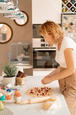 Genç bayan Paskalya pastasını kurutulmuş meyve ve kuru üzümle hazırlıyor.