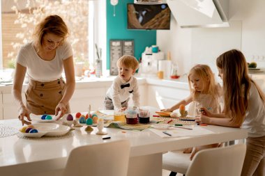 Anne ve kızları yumurta boyuyor. Mutlu aile Paskalya için hazırlanıyor..