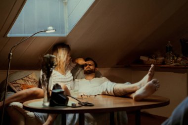 Genç aşıklar evlerinde kanepede kedileriyle rahat bir akşam geçirirler..