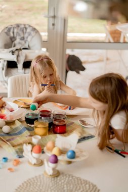Anne ve kızları yumurta boyuyor. Mutlu aile Paskalya için hazırlanıyor..