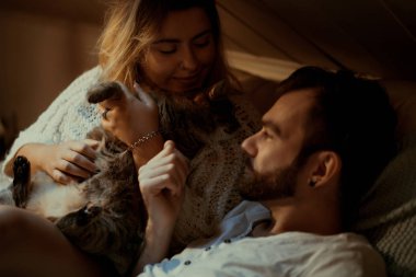 Genç aşıklar evlerinde kanepede kedileriyle rahat bir akşam geçirirler..