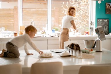 Mutlu aile Paskalya tatiline hazırlanıyor. Anne ve çocuklar mutfakta kek pişiriyor ve yumurta boyuyor. Evcil tavşanlar