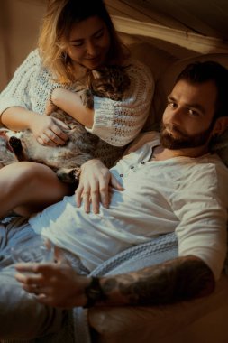 Genç aşıklar evlerinde kanepede kedileriyle rahat bir akşam geçirirler..