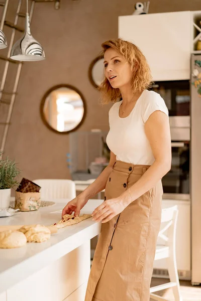 young woman prepares Easter cake with dried fruits and raisins