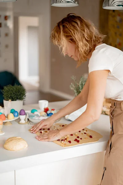 young woman prepares Easter cake with dried fruits and raisins