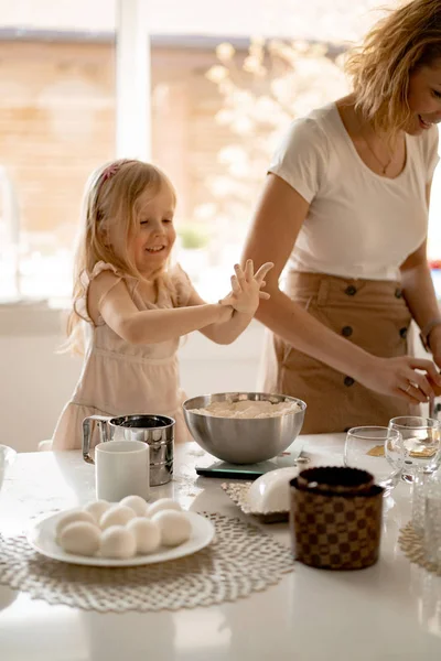 girl helps mom in the kitchen to cook Easter cakes.  Happy family preparing for Easter