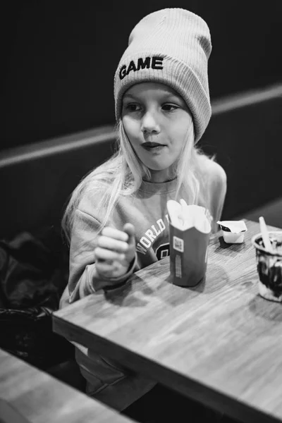 Bambini da McDonald's. La bambina mangia patatine fritte e bevande — Foto Stock