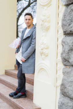 Bir buket pembe çiçekli erkek arkadaş, kar yağarken dışarıda kız arkadaşını bekliyor. Valenin gün konsepti, evlilik teklifi.