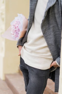 Bir buket pembe çiçekli erkek arkadaş, kar yağarken dışarıda kız arkadaşını bekliyor. Valenin gün konsepti, evlilik teklifi.